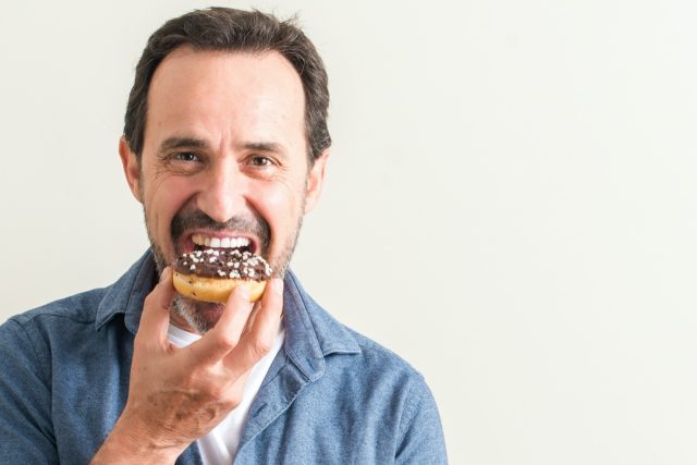 Senior man eating chocolate donut