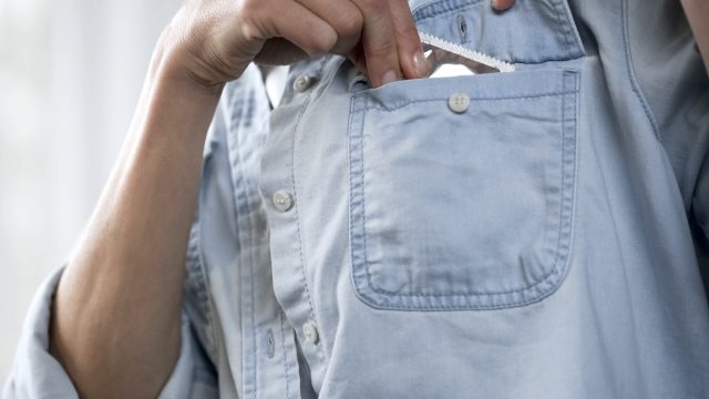Womans hand putting condom package in her pocket, contraception