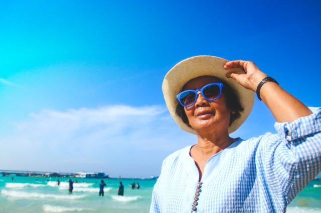 elderly women Wearing blue sunglasses Walking around the sea