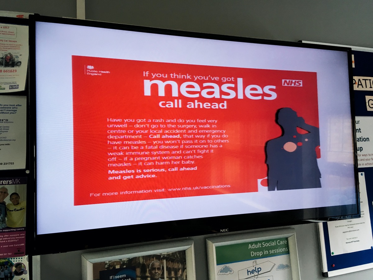 A sign warning people about measles in a NHS doctors surgery clinic
