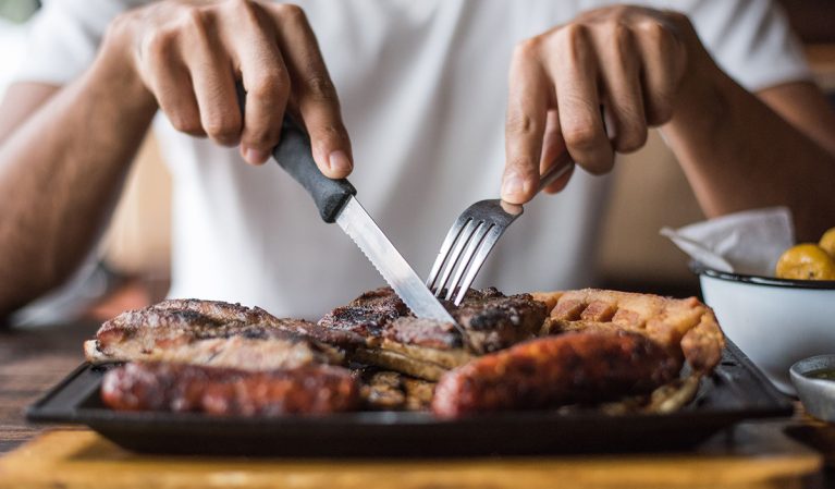 man cutting into steak with fork and knife