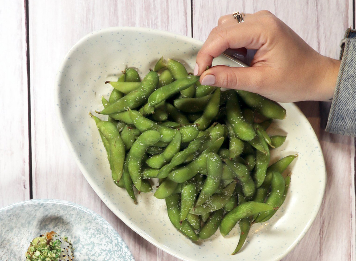 grabbing an edamame from a large bowl