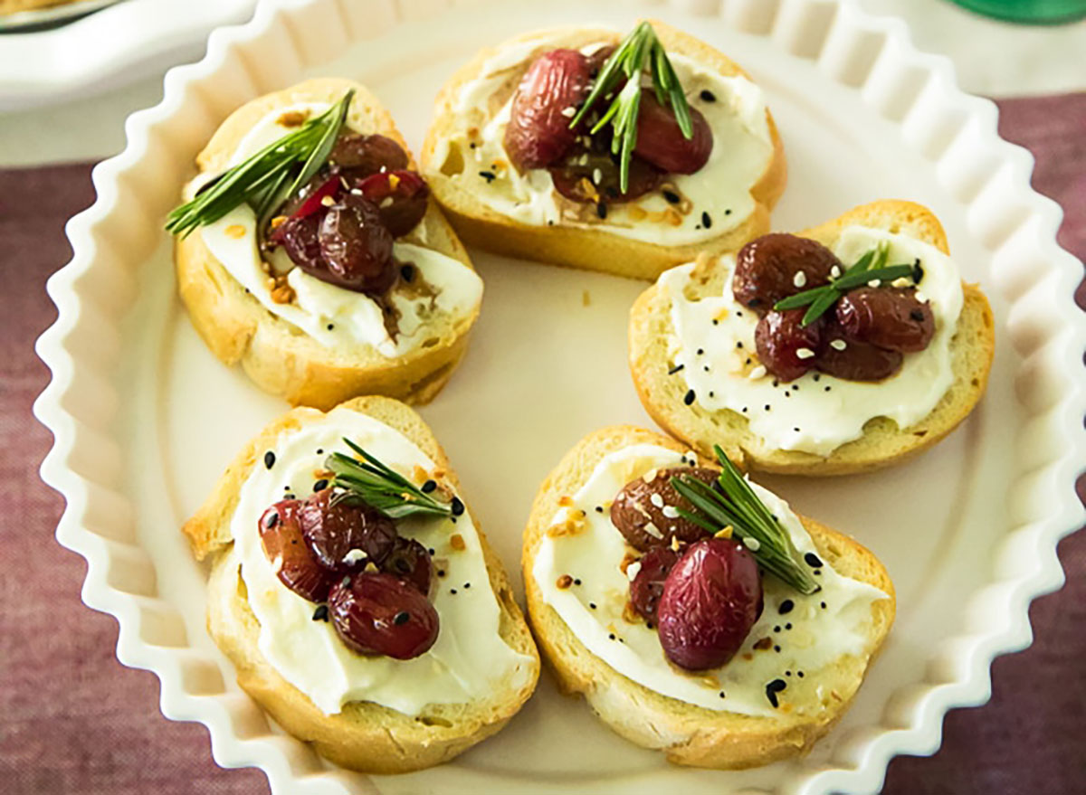 roasted grape crostini with sliced grapes and ricotta cheese in white serving dish