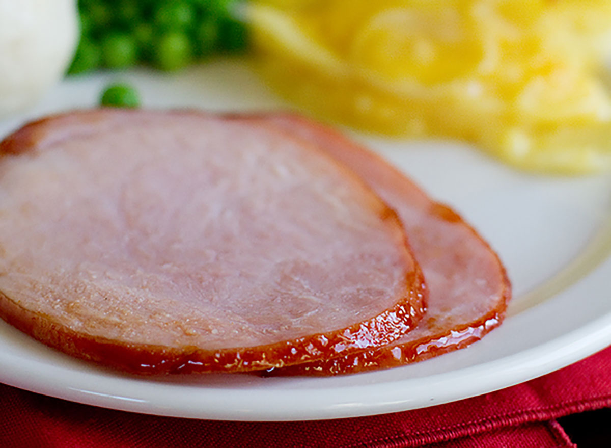 root beer glazed ham slices on plate with peas and potatoes