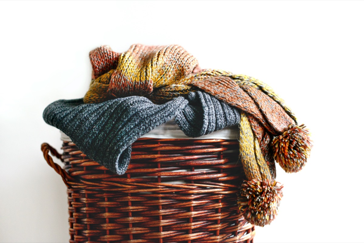 Pile of knitted winter scarfs on straw basket