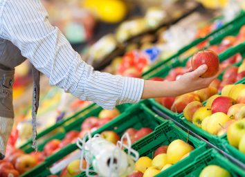 Shopper grabbing an apple at the grocery store