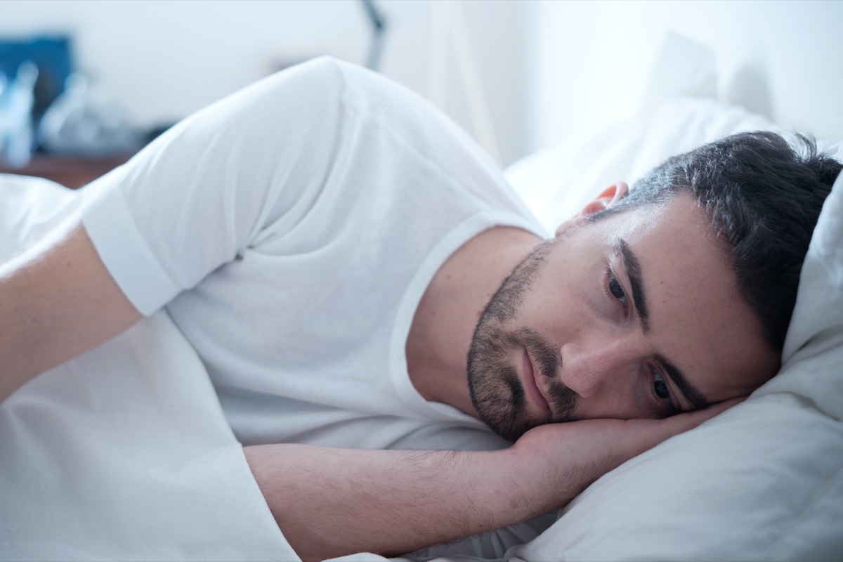 Depressed man lying in his bed and feeling bad