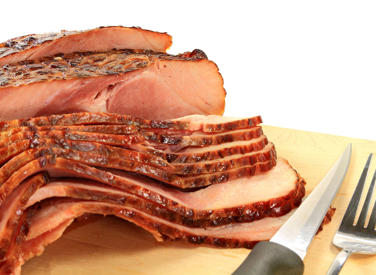 sliced glazed ham with fork and slicing knife