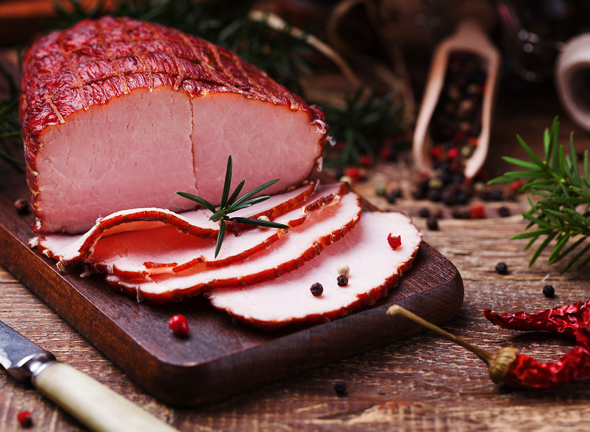 smoked ham on wooden cutting board with garnish