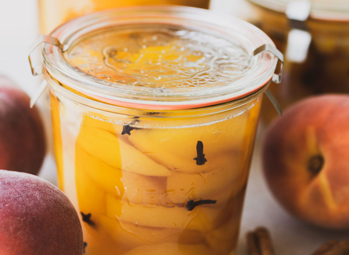 spiced peaches in glass jar with fresh peaches on the side