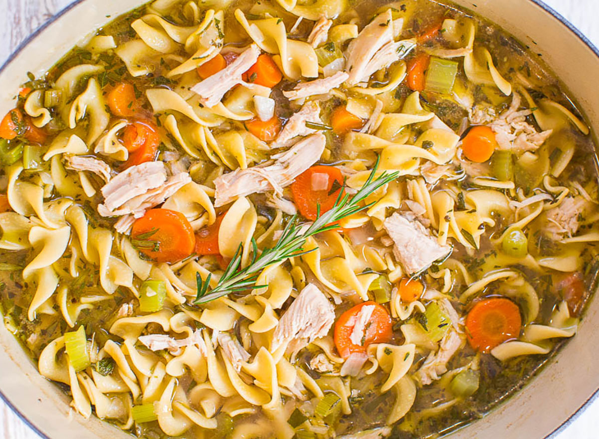 pot of turkey noodle soup with shredded turkey, noodles, carrots