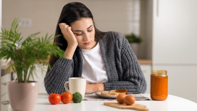 Displeased young woman doesn't want to eat her breakfast