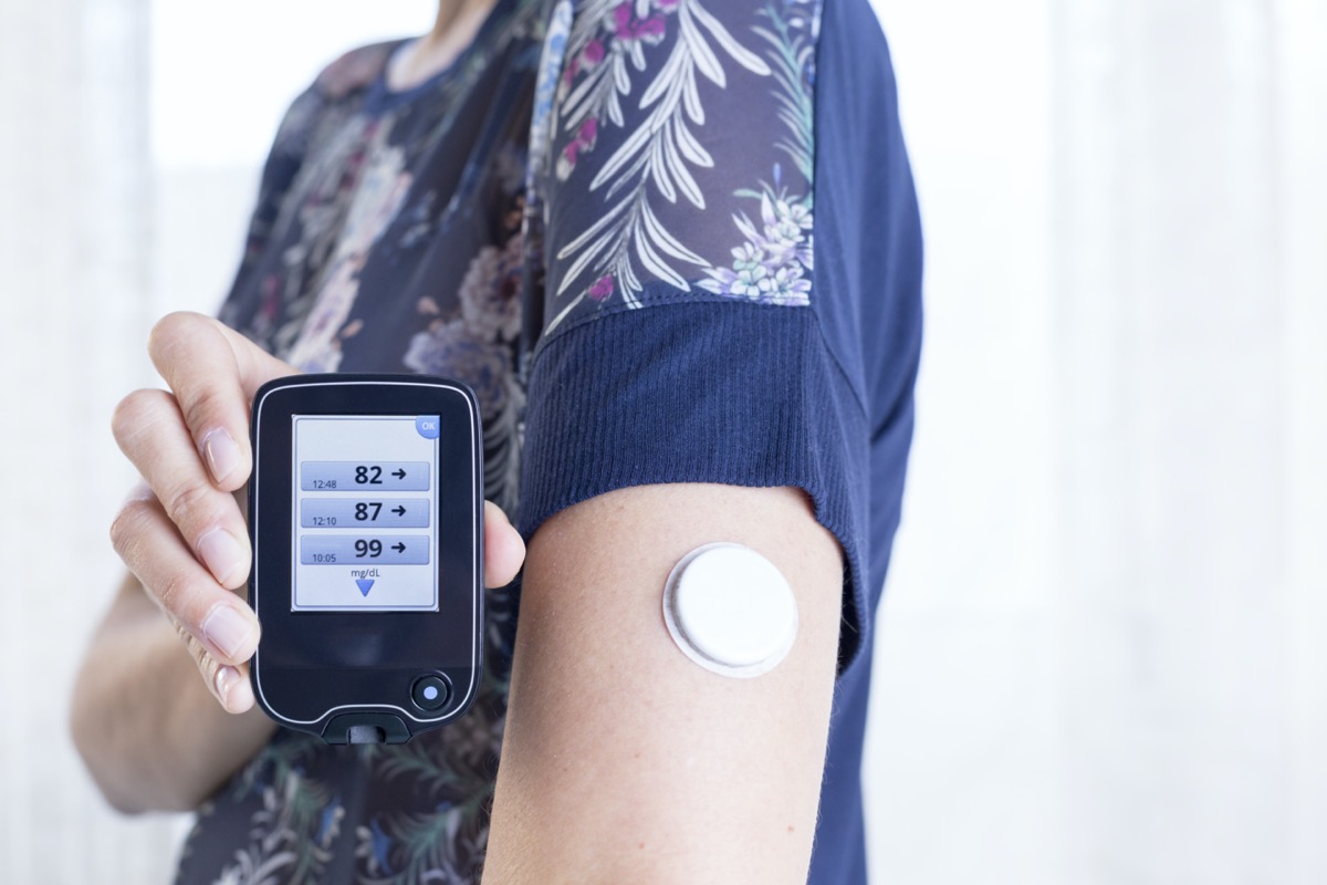 a hand of a young woman showing the reader after scanning the sensor of the glucose monitoring system