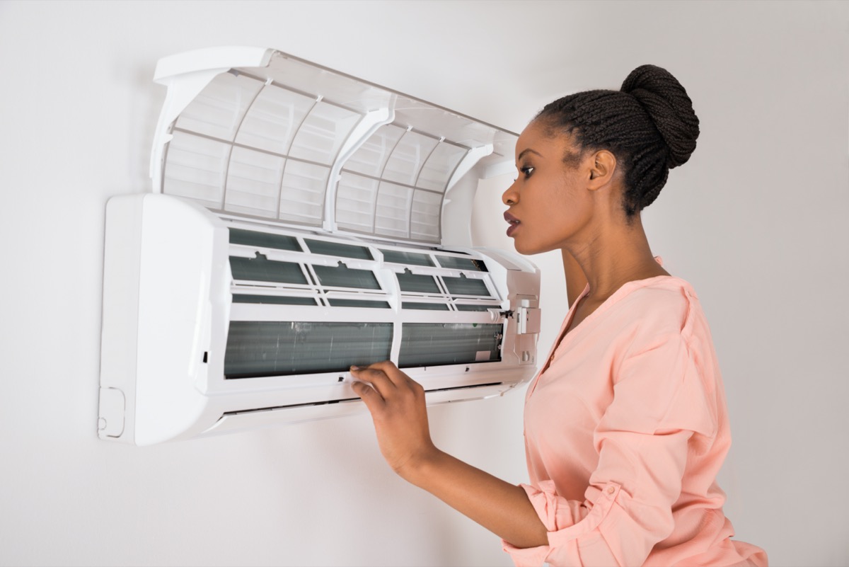 Woman Checking Air Conditioner At Home