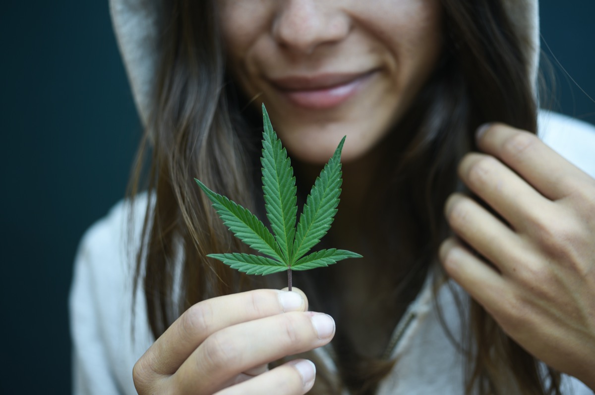 Woman holding marijuana leaf hand
