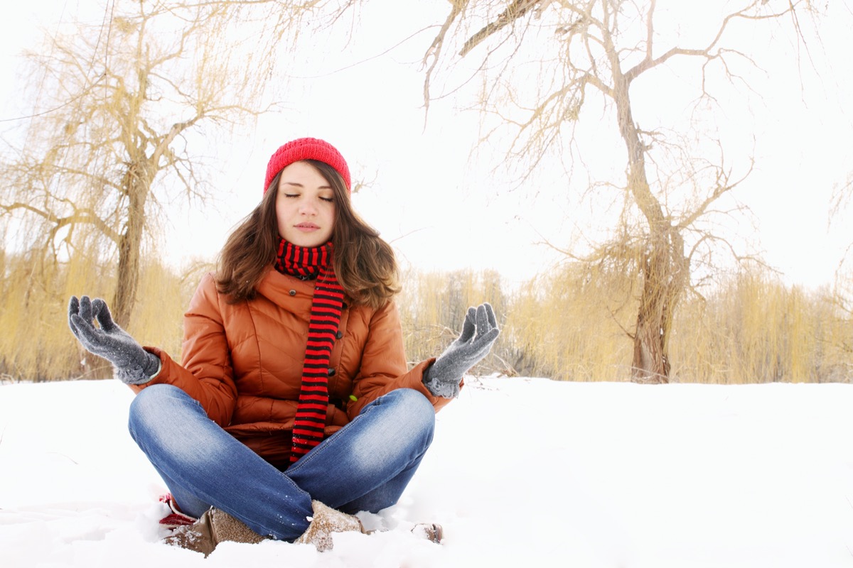 girl in lotus pose in the snow