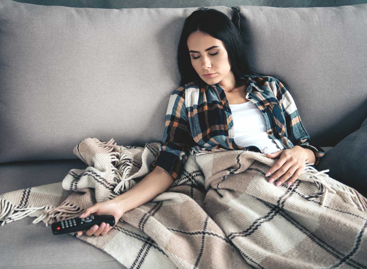 Young woman sleeping passed out on couch after watching tv with a food coma