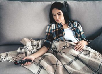Young woman sleeping passed out on couch after watching tv with a food coma