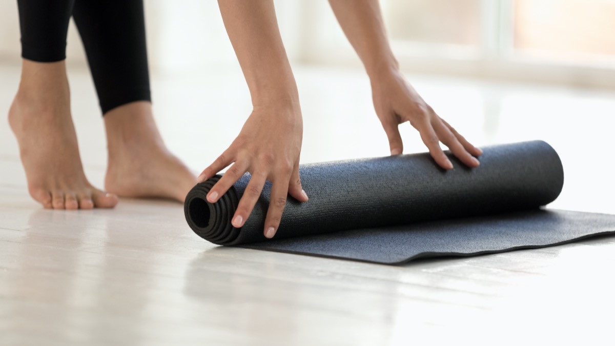 Donna che indossa leggings neri finito o di partenza allenamento rotolamento mat
