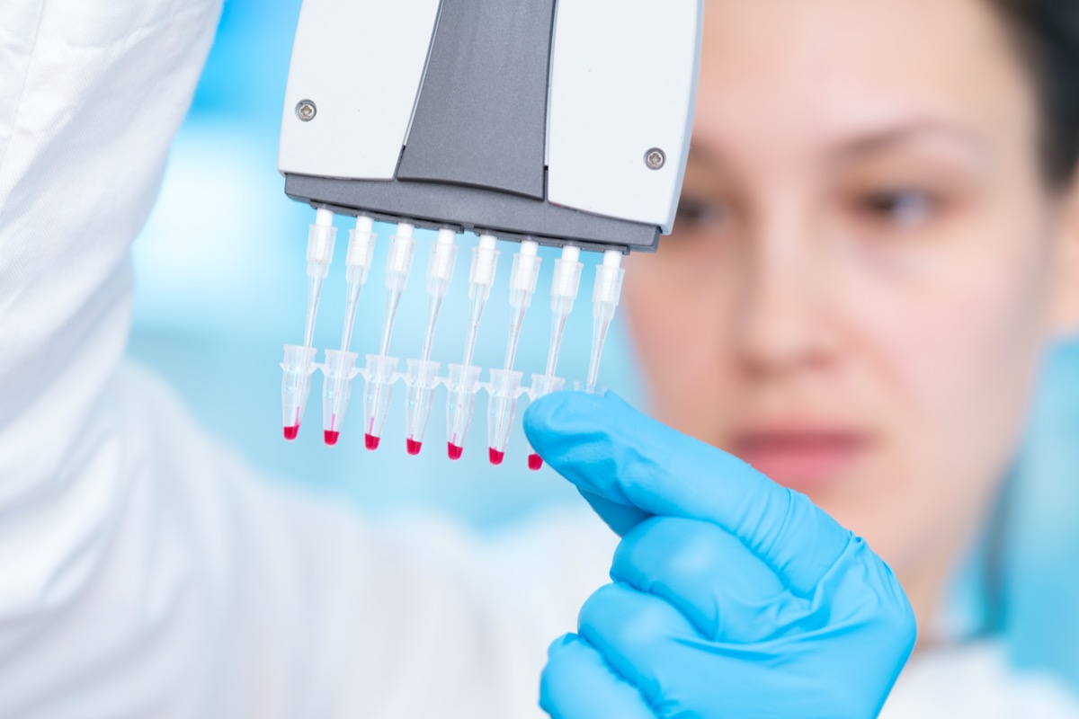 Woman technician with multipipette in genetic laboratory PCR research