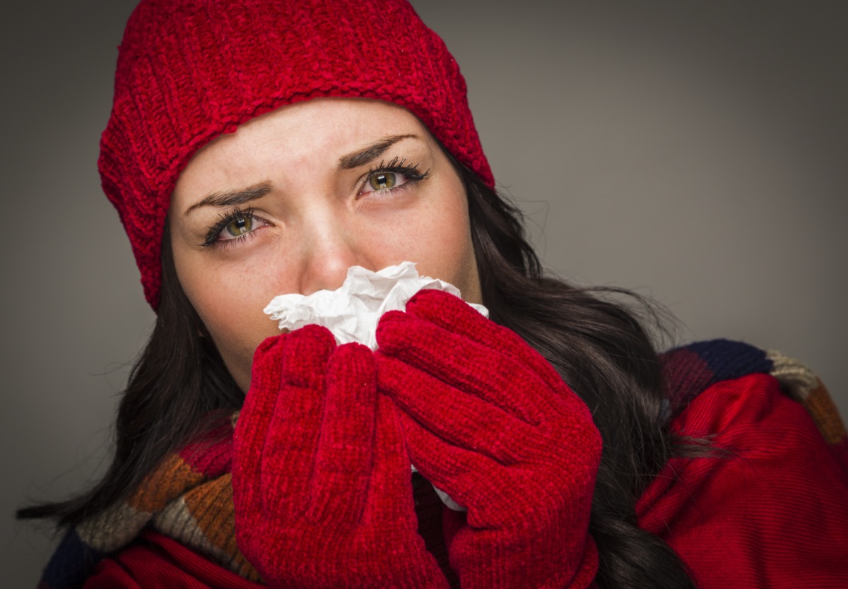 Woman Wearing Winter Hat and Gloves Blowing Her Sore Nose with a Tissue