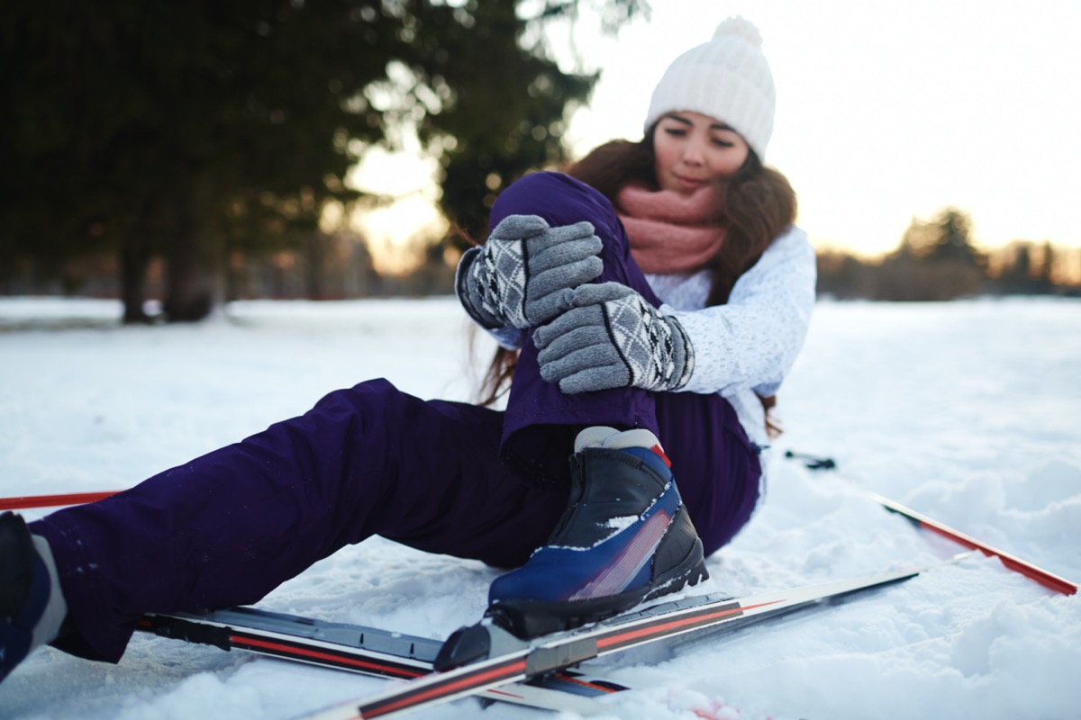 Fallen skier holding by her leg