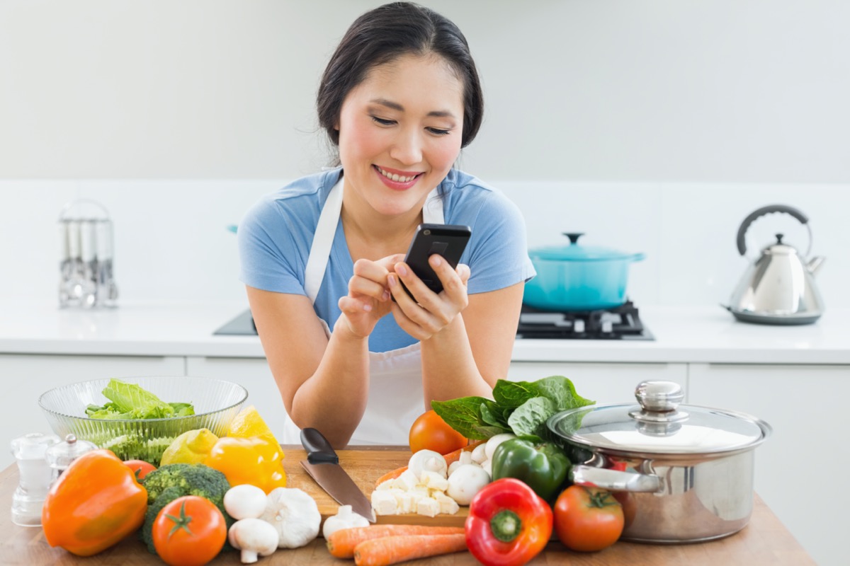man text messaging in front of vegetables in the kitchen at home