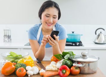 man text messaging in front of vegetables in the kitchen at home