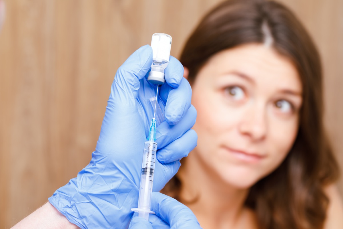 Medical assistant preparing an intramuscular injection of a vaccine in a clinic