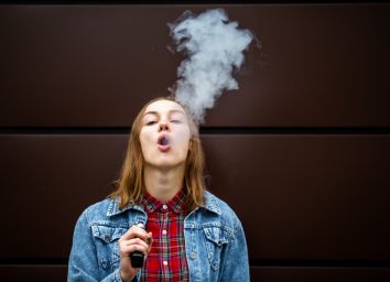 girl in casual clothes smoking an electronic cigarette