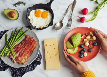 Woman holding plate of keto foods at a table