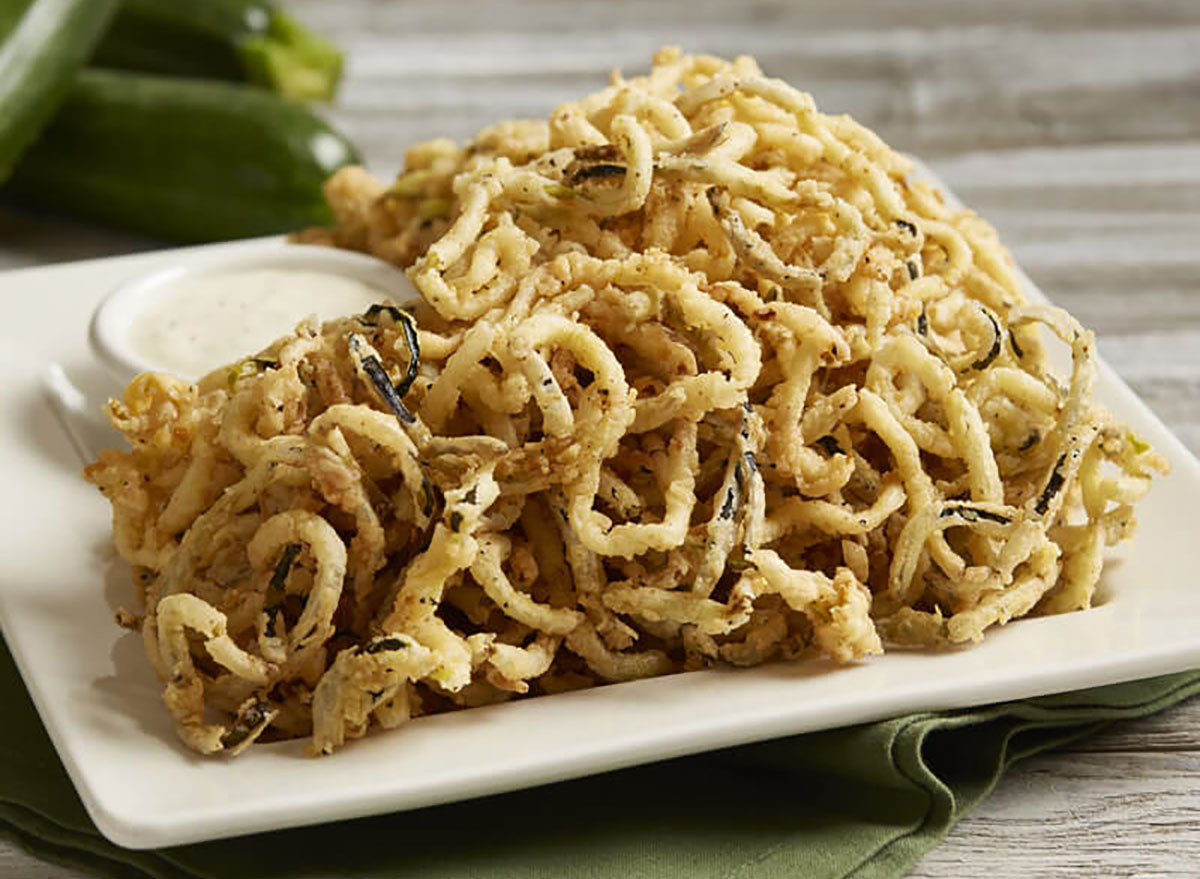 curly fried zucchini strings with dipping sauce on serving plate