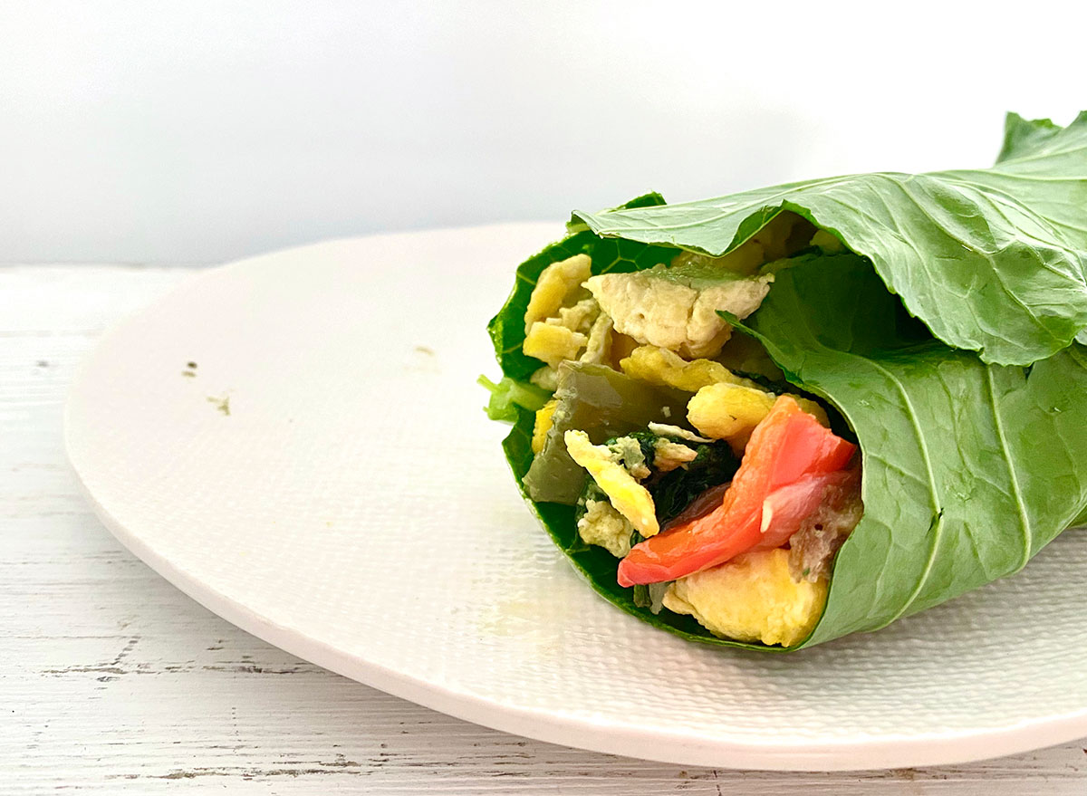 whole30 breakfast burrito on a white plate wrapped in a collard green