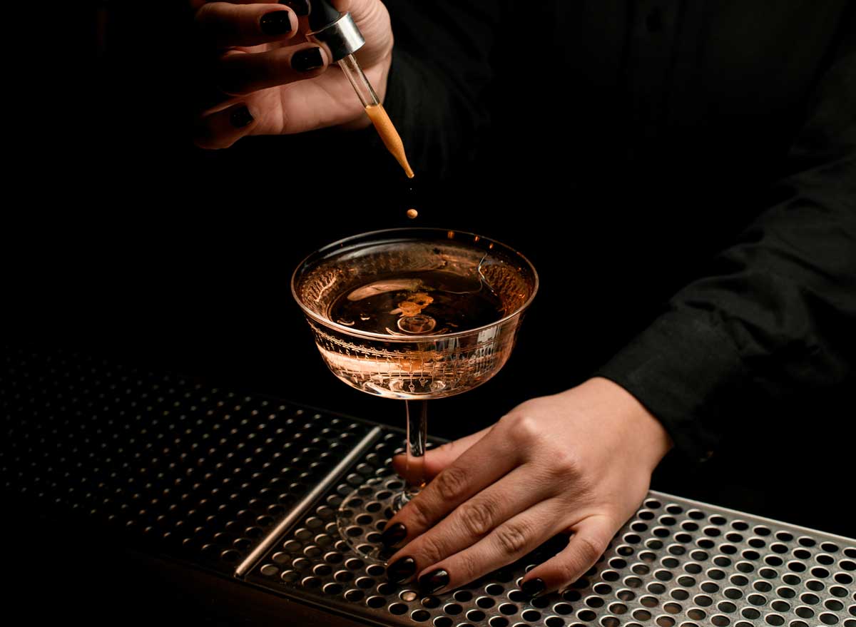 Bartender adding bitters to cocktail