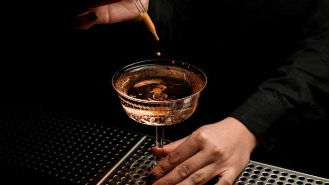 Bartender adding bitters to cocktail