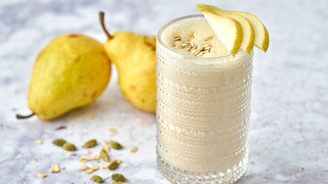 cardamom pear smoothie in glass garnished with pear