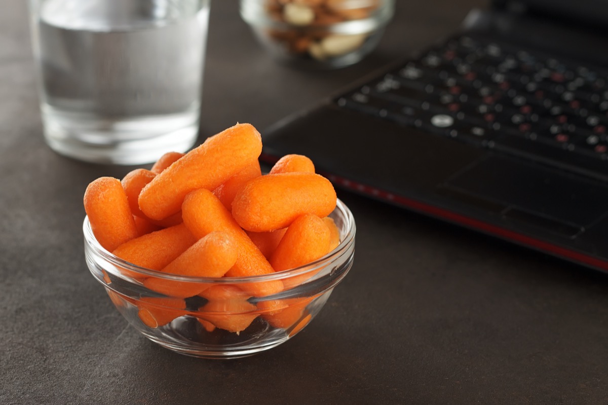 Healthy snacks for office lunch: baby carrots, almonds, cashew and glass of water.