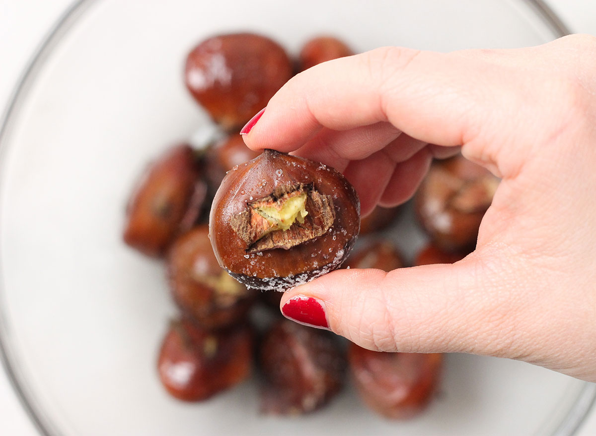 picking up a chestnuts from a bowl getting ready to peel it