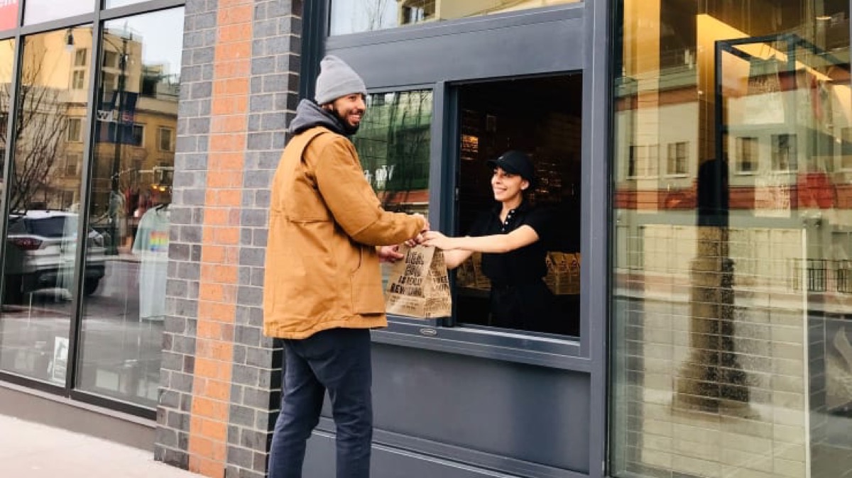 a man ordering a burrito or possibly a burrito bowl at a chipotle walk-through window