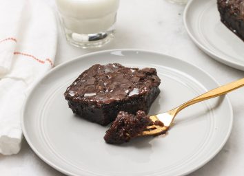 biting into a slice of coca cola cake on a grey plate