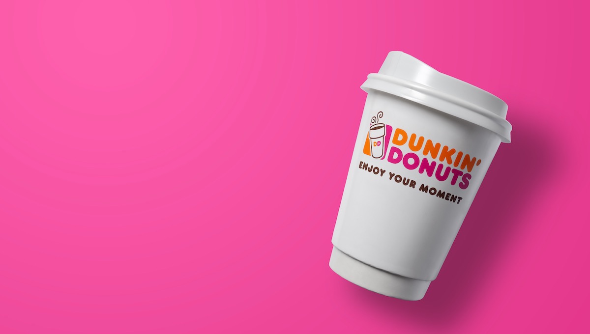 a dunkin donuts cup against a pink background