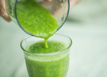 green smoothie being poured from blender into glass