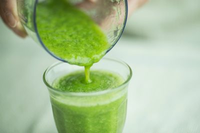 green smoothie being poured from blender into glass