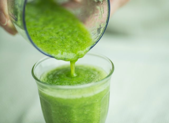 green smoothie being poured from blender into glass