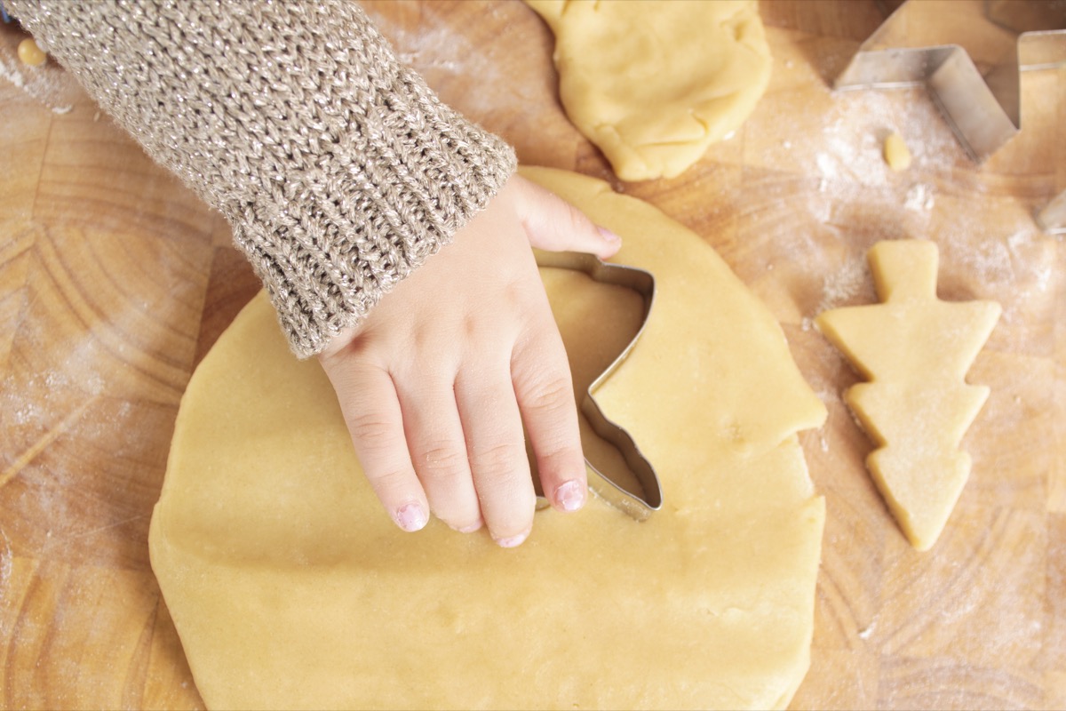 a hand pushing an angel cookie cutter into cookie dough to make baby yoda cookies