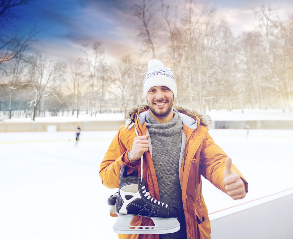 man with ice-skates showing thumbs up on skating rink