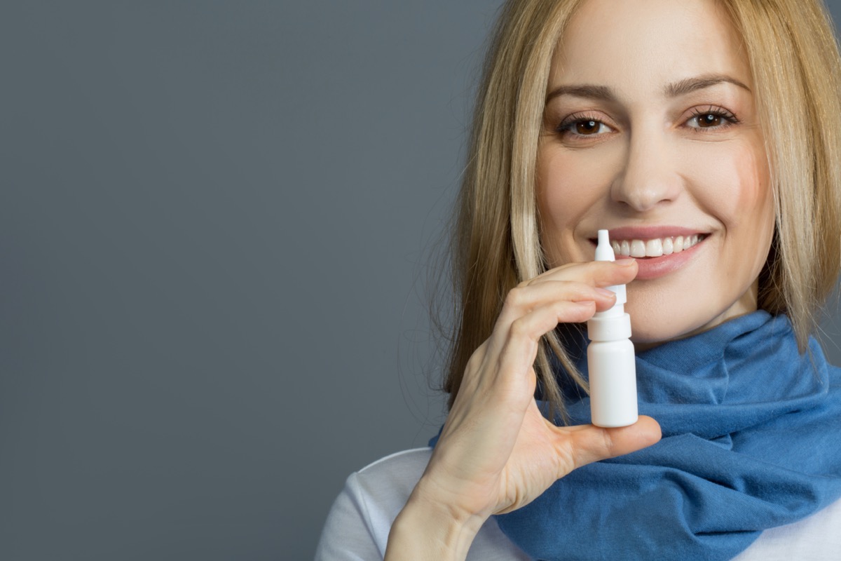smiling girl in blue scarf holding nasal spray