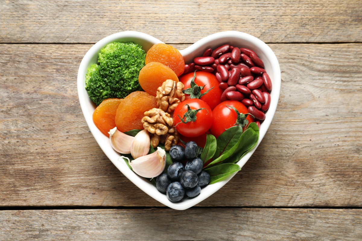 Bowl with products for heart-healthy diet on wooden background