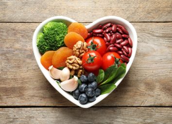 Bowl with products for heart-healthy diet on wooden background