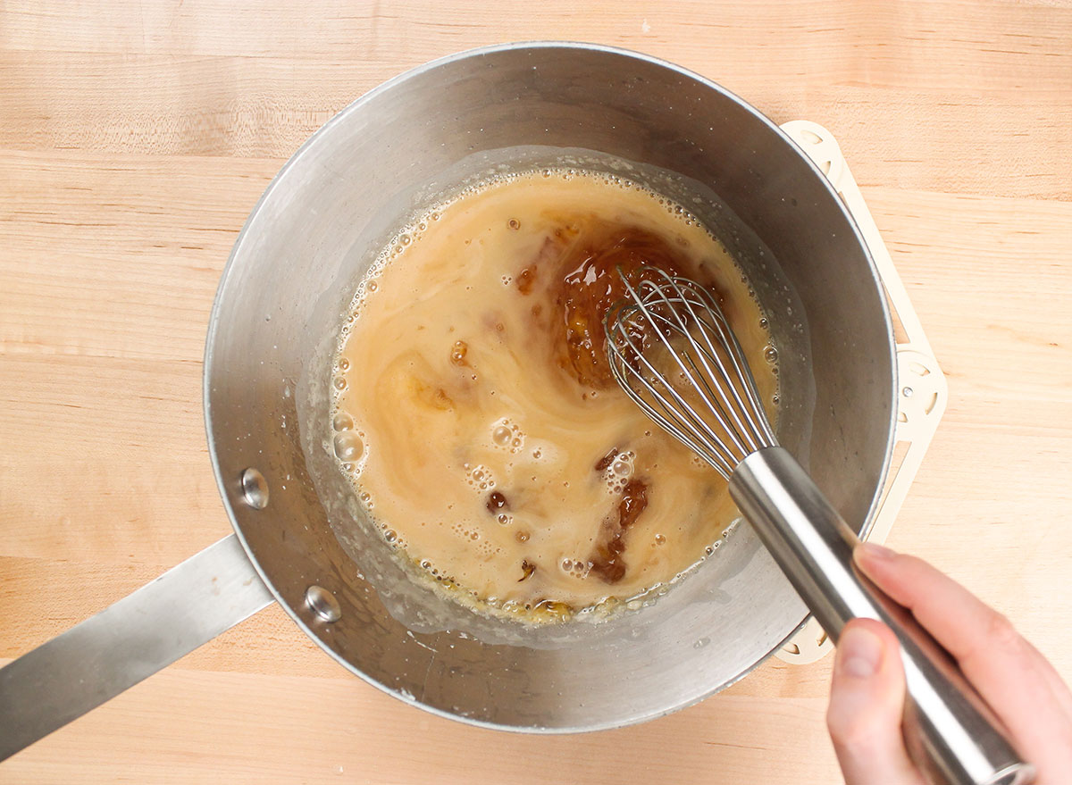Whisking cooked sugar and water for caramel in a pot